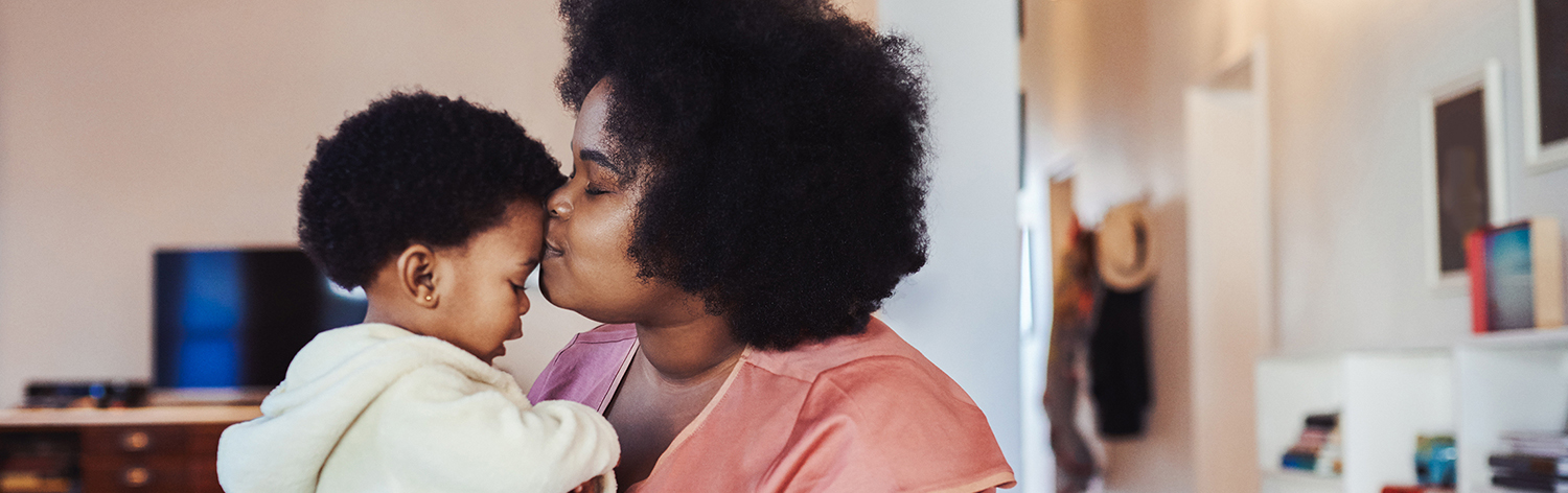 Mother kisses toddler on forehead