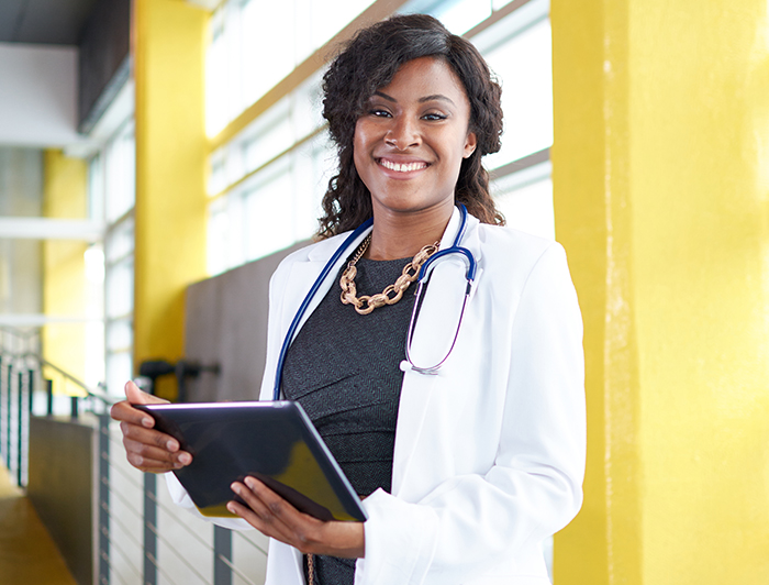 Comprehensive Perinatal Care. A physician holding a tablet stands in a hospital room.