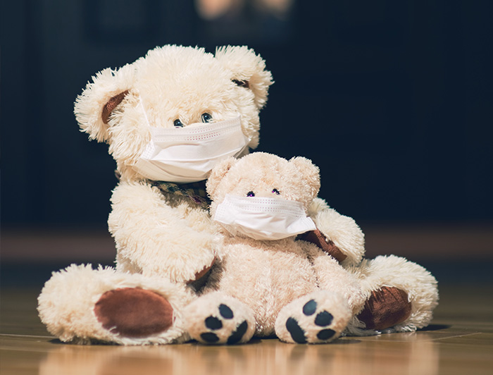 Two teddybears - adult embracing child, both with face masks on