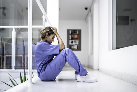 stock photo of health worker on hospital floor with head in hands