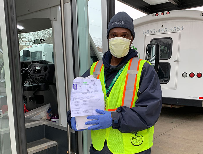 PACE bus driver with a mask on holding a paper up