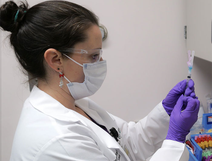Masked health worker fills a syringe