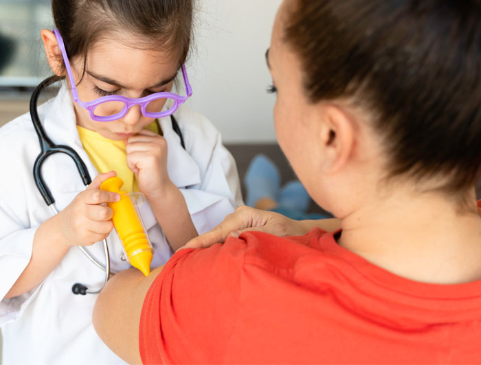 child dressed as doctor administers shot in arm to a woman in this stock photo