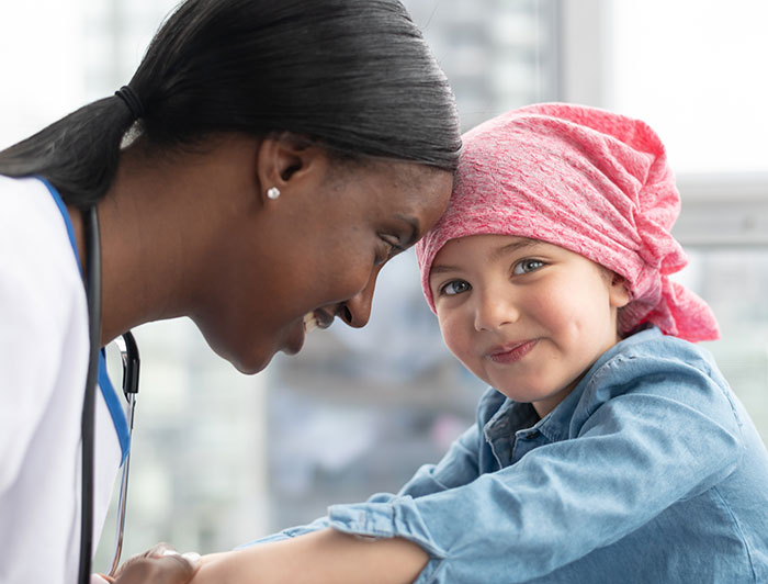 Nicklaus Children's Hospital. A doctor leans touches her forehead to a child's forehead. The child is wearing a scarf on her head.