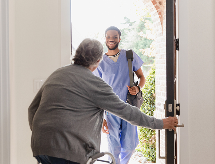 Providence Health System. An elderly patient opens their front door to greet a smiling home caregiver