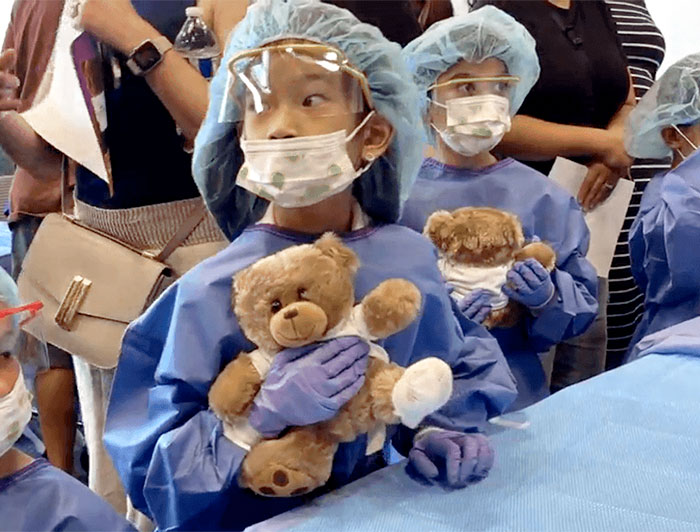 Southern Hills Hospital pediatric patients wearing PPE sit holding teddy bears at an event
