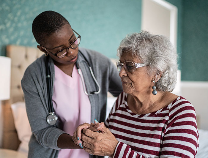 Stephens County Hospital. A female clinician sits in a residential setting with an elderly woman.