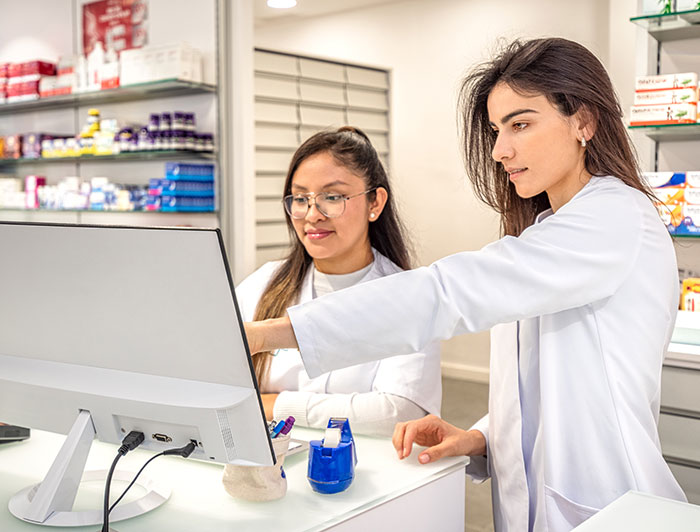 Denver Health. Two female health workers in white coats look at a computer screen.