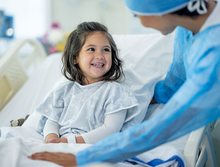 Fairview Park. Stock image of a small girl smiling up from her hospital bed at a female doctor in scrubs