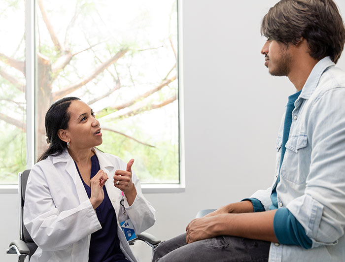 Hartford HealthCare. A female doctor gestures with hands while consulting with a male patient.