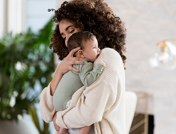 Loma Linda University Medical Center-Murrieta. Young curly-haired mother holds her infant against her shoulder
