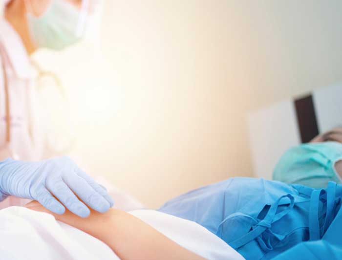 Crestwood Medical Center nurse holding a patients hand in bed