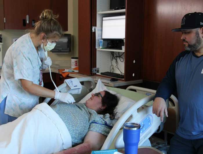 Nusre checking on a patient with loved one nearby