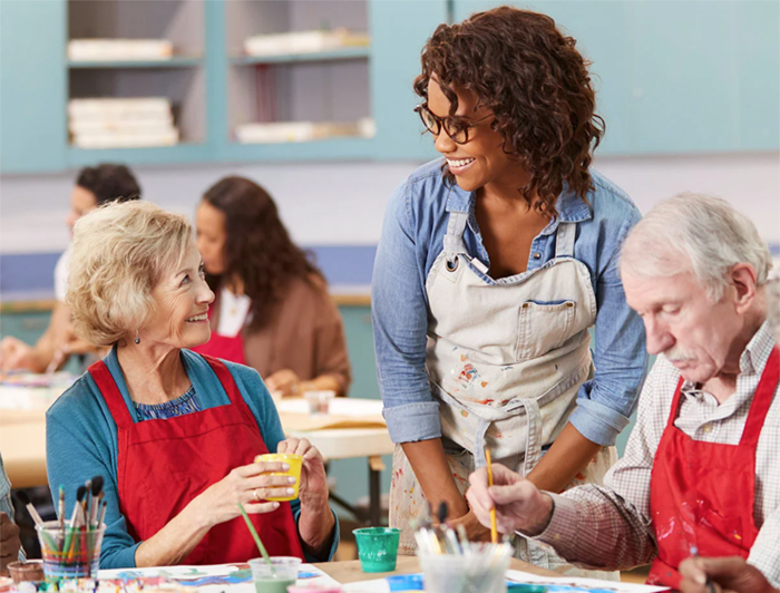 Dartmouth Health. A female art teacher stands talking to an older woman seated at a craft table
