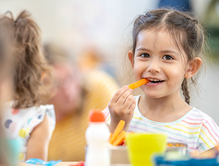 Arkansas Children’s Hospital. A smiling young girl sits at a school dining table eating a nutritious meal