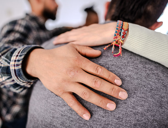 Mass General. tock photo of arms around the shoulders of a group counseling participant