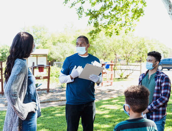 Telling the Hospital Story: INTEGRIS Health Mobile health clinic helps bridge access to care in Oklahoma communities. Stock image of male health worker outdoors at a rural event, speaking with community members