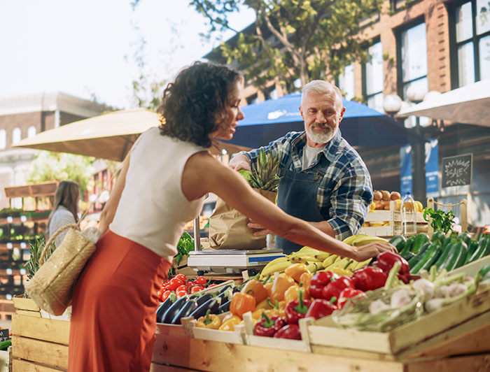 St. Tammany Health System. Woman checks fresh produce at a farmer's market as vendor looks on