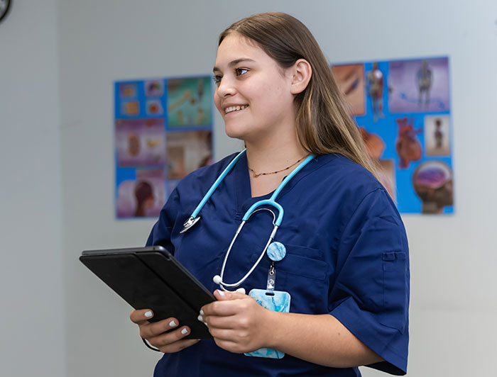 Grand Itasca Clinic & Hospital. A woman wearing scrubs and a stethoscope stands holding a tablet
