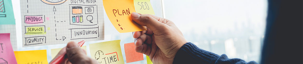 Close-up of ideas board, with some copy visible like; Product, Service, Quality, Innovation and sticky-notes with Plan and SEO