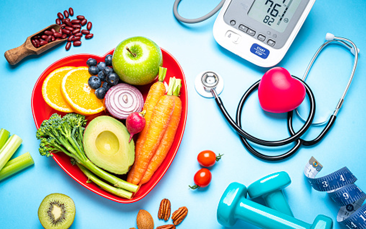 3 Ways Food Is Medicine Network Will Drive Change. Vegetable and fruit on a heart-shaped plate, a wooden scoop filled with red beans, a heart-shaped foam stress toy, blue rubber-coated hand weights, a stethoscope, a blood-pressure gauge, and tailor's measuring tape.