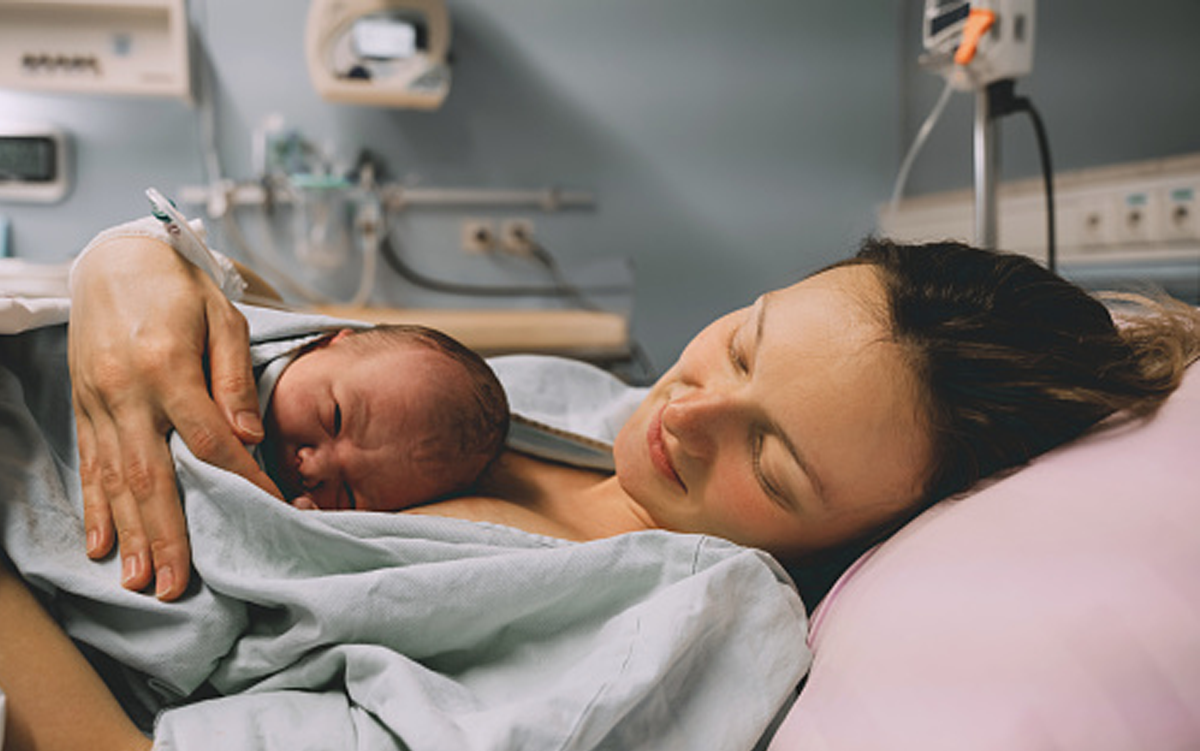 AHA, Epic Launch Tools to Help Improve Maternal Health Outcomes. A mother lies in a hospital room with her baby on her chest after the baby was delivered.