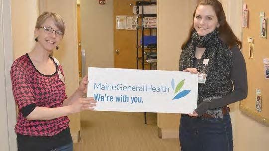 Two MaineGeneral staff members hold a banner that reads, "MaineGeneral Health. We're with you."