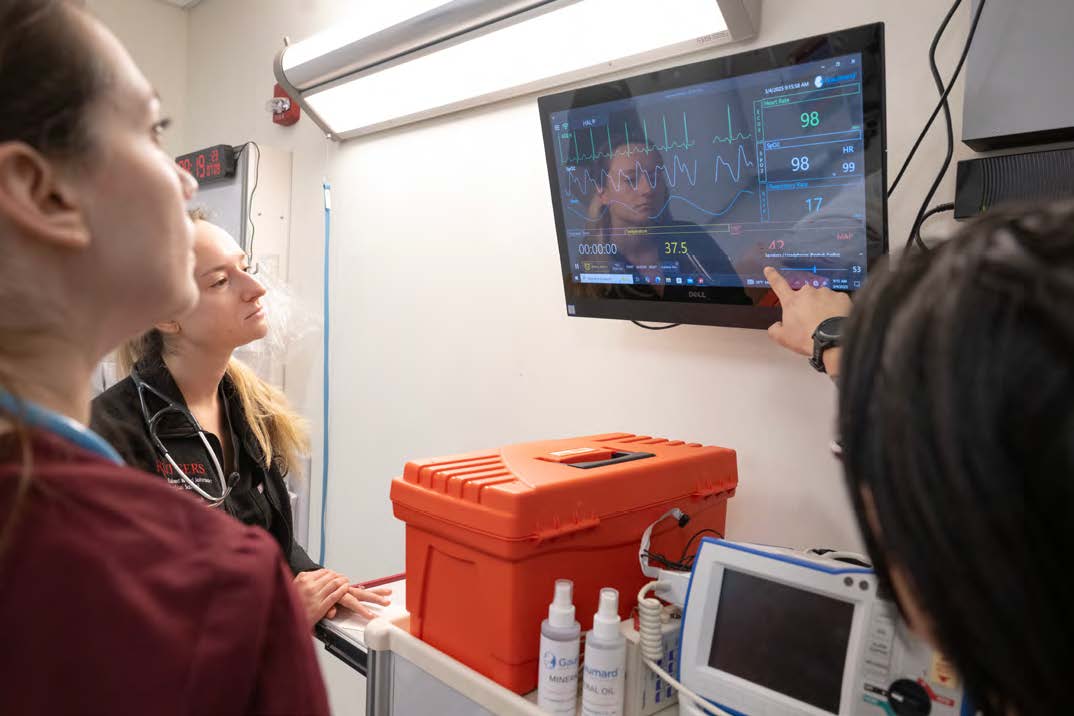 Clinicians at Rutgers Health observe a monitor with EMR data on it augmented by the Clinical Deterioration Index (CDI), a predictive algorithm that continuously analyzes EMR data such as vitals, labs, and clinical notes to identify early signs of patient decline.