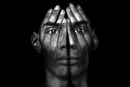 Make Behavioral Health More Accessible: Are You Up for the Challenge? A man's face projected on a pair of hands covering a person's face.
