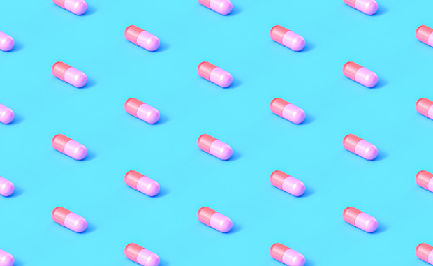Will Startup PBMs Drive Drug Price Transparency? Drug capsules aligned in in straight rows and columns on a blue background.