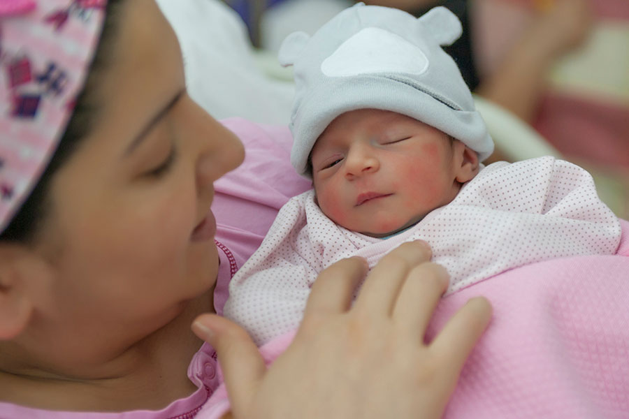 Better Health for Mothers and Babies. A mother holds her newborn child in a hospital bed.