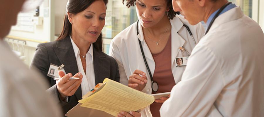 hospital staff and administrator looking at legal pad in hallway