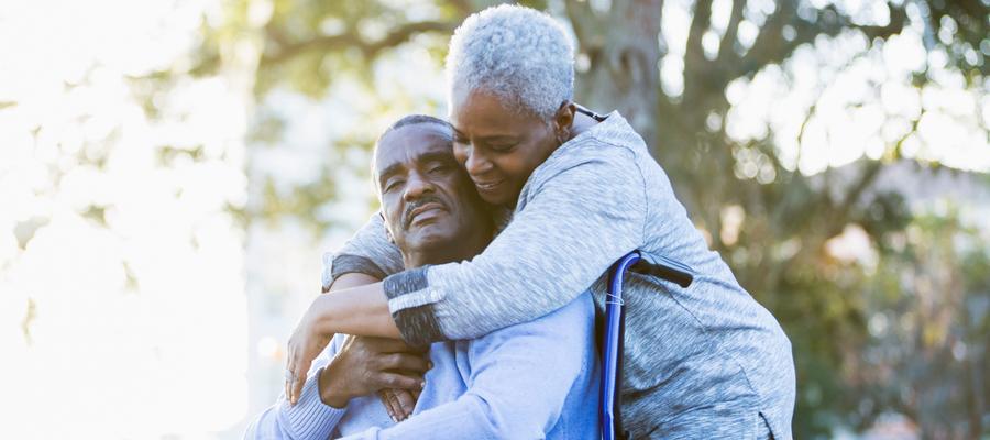 Woman hugs man in wheelchair
