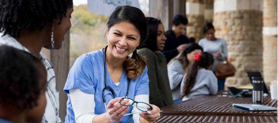 A girl and her mom sit with a health care provider at an eyeglasses drive.