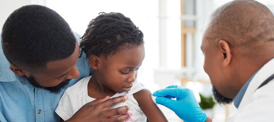 Child gets injection from doctor while on dad's lap