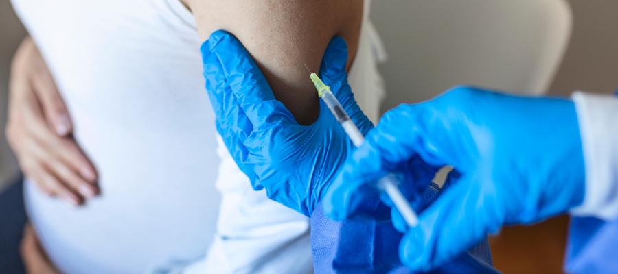 A woman with a baby bump receives a vaccine. 