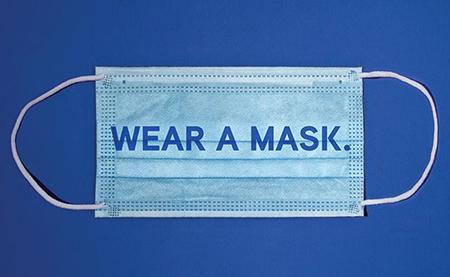 surgical mask on blue background with "wear a mask." superimposed on it.