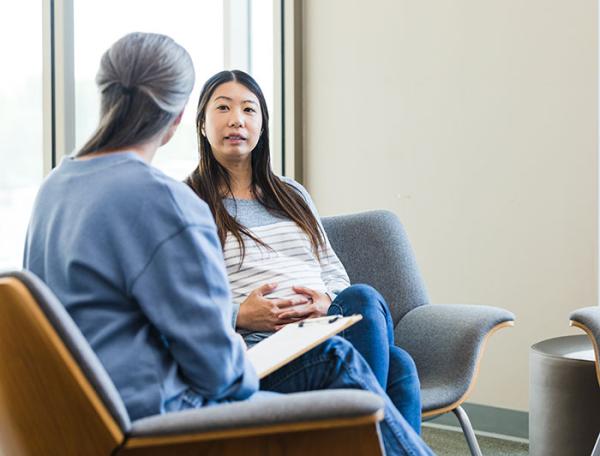 Stock image of a pregnant woman talking to a clinician in an office