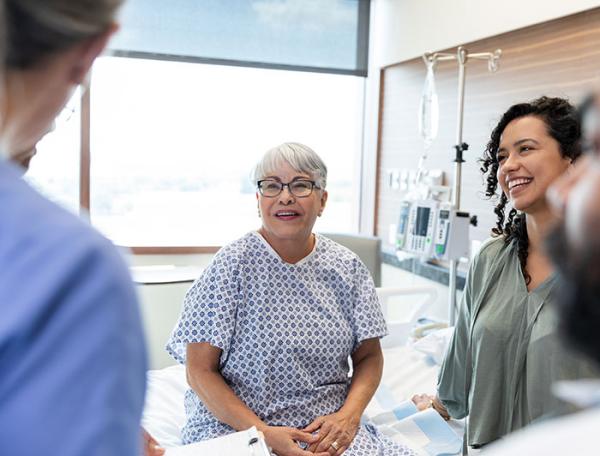 An older adult woman and her family listen attentively to a doctor in a hospital room