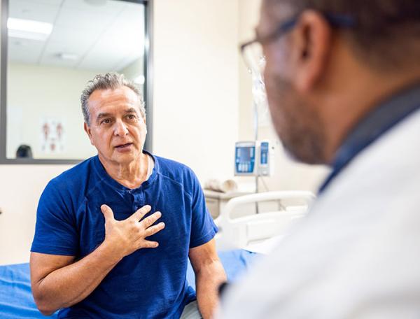 An older man speaks with an older male physician