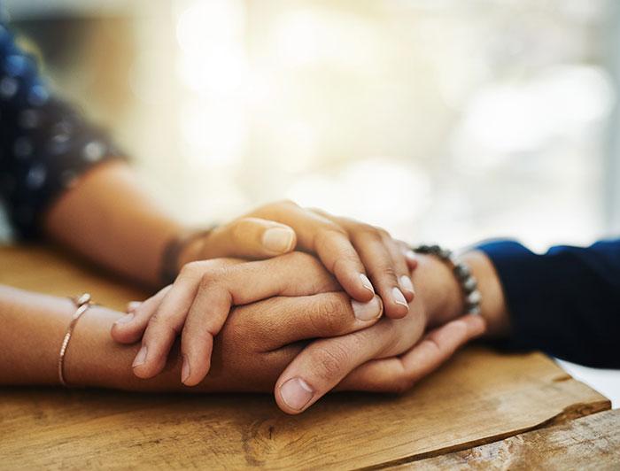 close shot of hands held across a wooden table