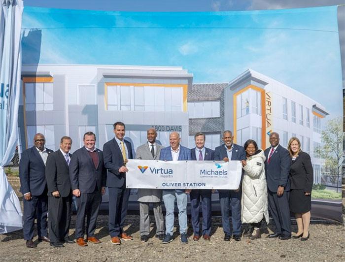 Virtua, Michaels leaders at groundbreaking stand ouside in front of a large rendering