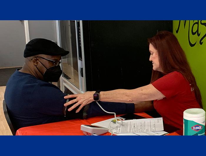 Indiana University Health clinician checks patient's blood pressure at a barbershop