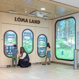 Children and a woman view Loma Linda University Children's Hospital experience the interactive Loma Land exhibit