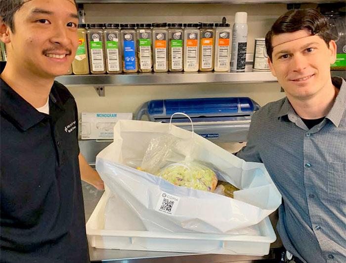 Sutter employees stand in a kitchen with bags of food
