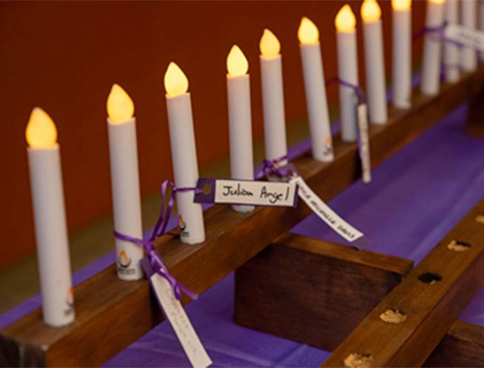 candles lit in memory of lost children bear names tied on with purple ribbon