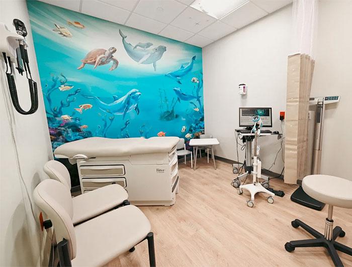 A new examination room in a family medical center sports new furnishings and an mural of ocean life