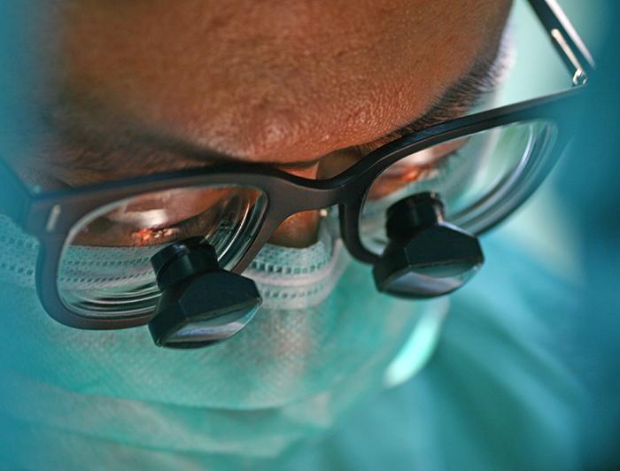 stock image - closeup of a surgeon working in surgical magnifying glasses 