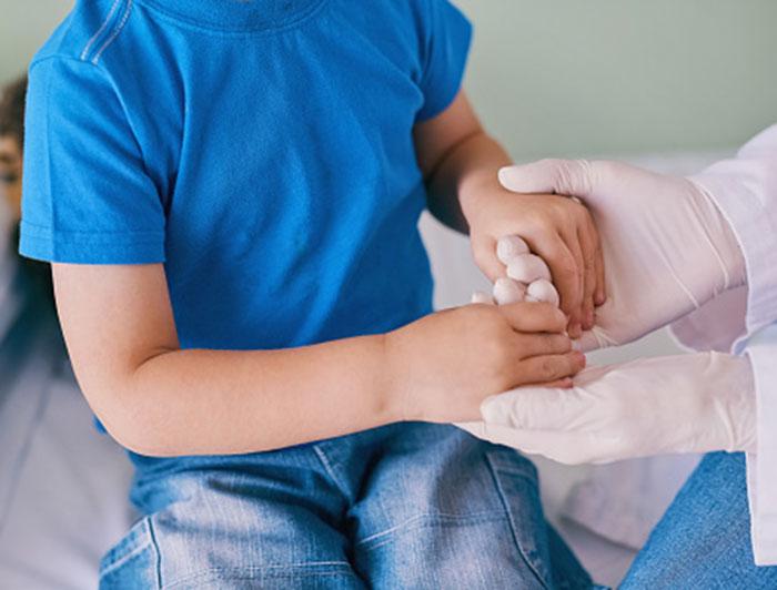 UC Davis Health Doctors Use Collarbone to Create New Upper Arm for Young Patient. A doctor in gloves holds the hands of a young patient to test the strength in his arms and hands.