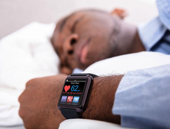 stock - man sleeps while wearing a smartwatch, which is in focus in foreground